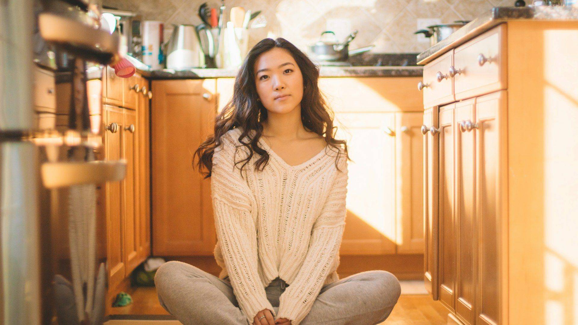 Woman sitting on her kitchen floor in afternoon light, the mental load women carry