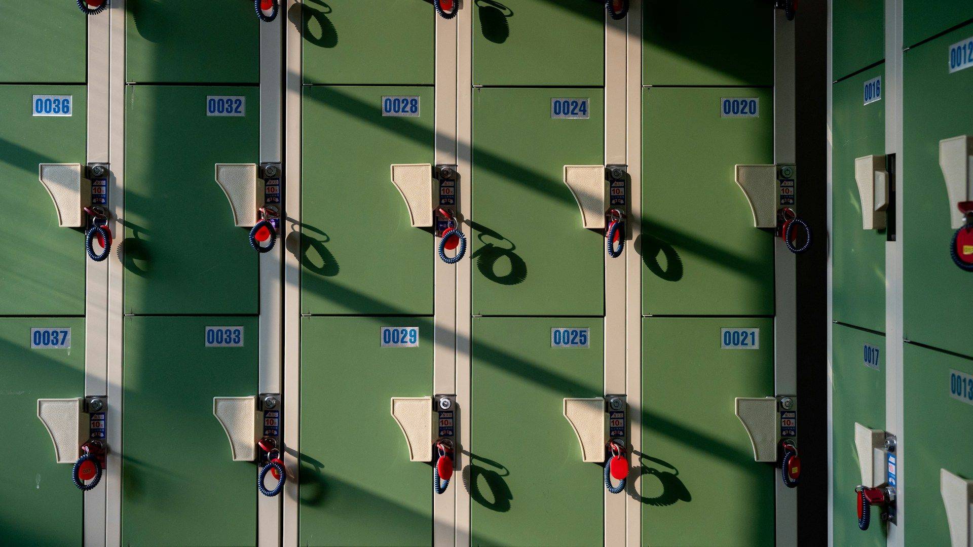 Row of green school lockers with sunlight and shadows across them